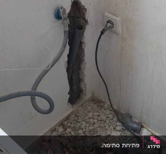 צינור מים חשוף בקיר עם חור ותשתית שבורה